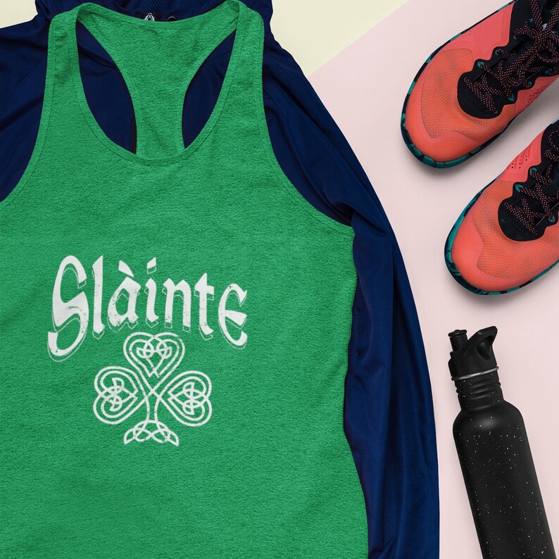 Celebrate St. Patrick’s Day in style with this Sláinte Celtic Knot Racerback Tank Top! Designed with a slim fit for a flattering look, this women's tank features a unique Celtic knot design symbolizing Irish and Scottish heritage. Perfect for pub crawls, parties, and festive celebrations, this Irish gift is a must-have for those who love to raise a toast in style!