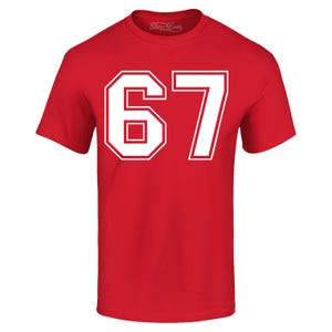 May include: A red t-shirt with the number "67" in white block letters. The number is outlined in white and has a rectangular shape inside the "6". The shirt has short sleeves and a crew neck.