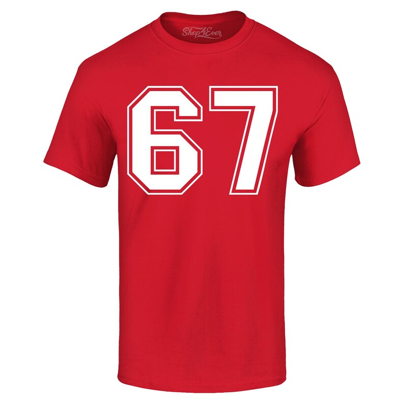 May include: A red t-shirt with the number "67" in white block letters. The number is outlined in white and has a rectangular shape inside the "6". The shirt has short sleeves and a crew neck.