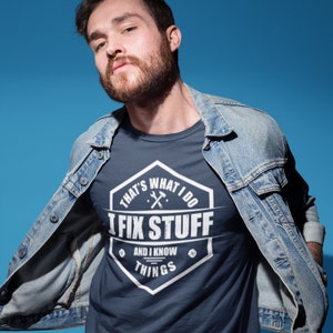 May include: A navy blue t-shirt with a white graphic of a hexagon with the text "That's What I Do I Fix Stuff And I Know Things" and a wrench and hammer inside the hexagon.
