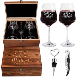 Puede incluir: Un juego de caja de regalo de madera con dos copas de vino llenas de vino tinto, un tapón en forma de corazón y un sacacorchos. Las copas y la caja están grabadas con nombres y una fecha.