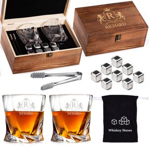 May include: A wooden gift set for whiskey lovers, including two engraved glasses, stainless steel ice cubes, tongs, and a wooden box. The glasses and box are personalized with a crest and the name "RICHARD". A black bag with the text "Whiskey Stones" is also included.