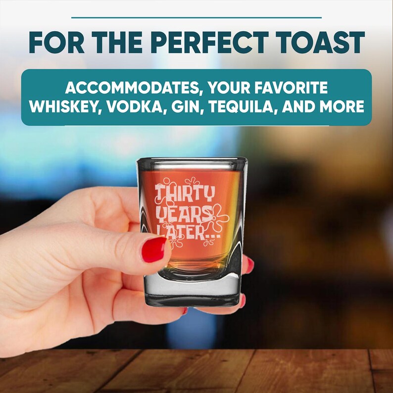 Peut inclure: Un verre &agrave; shot transparent avec le texte "THIRTY YEARS LATER..." en blanc. Le verre est rempli d'un liquide orange. L'image comprend &eacute;galement le texte "FOR THE PERFECT TOAST" et "ACCOMMODATES, YOUR FAVORITE WHISKEY, VODKA, GIN, TEQUILA, AND MORE".