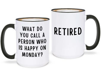 May include: Two white ceramic mugs with black handles and rims. One mug has the text "WHAT DO YOU CALL A PERSON WHO IS HAPPY ON MONDAY?" in black. The other mug says "RETIRED" in black.