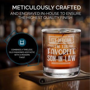 May include: A clear glass tumbler with a white inscription that reads "It's Official - I'm the Favorite Son-in-Law". The tumbler is filled with a brown liquid and ice.