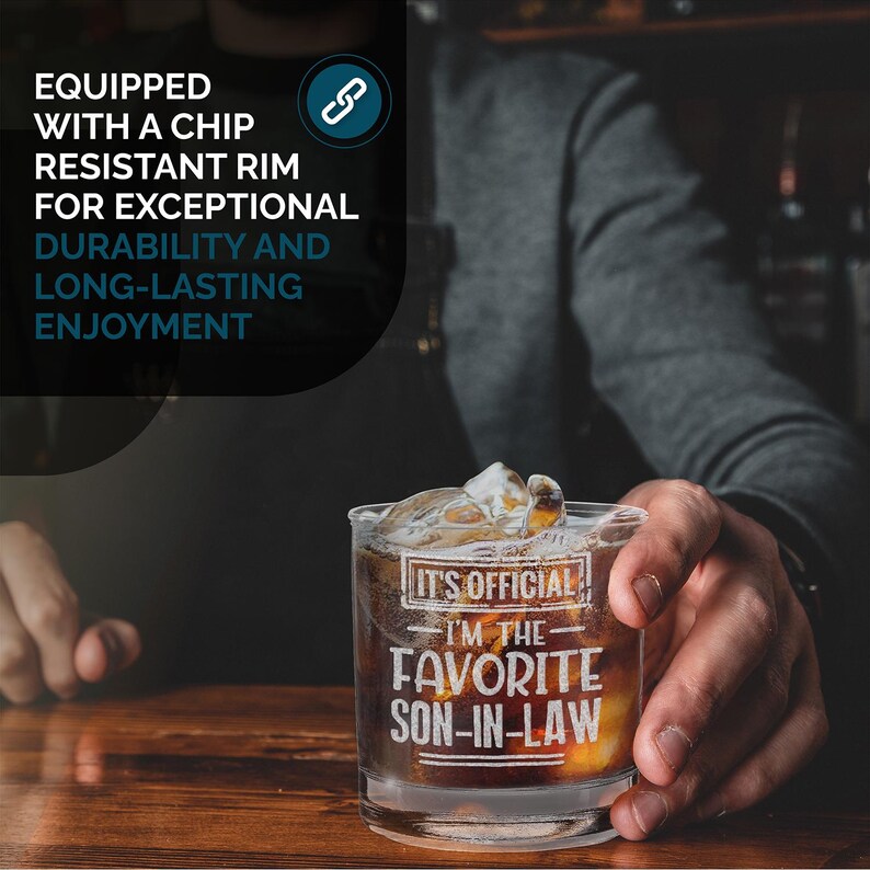 May include: A clear glass with a thick bottom and a design that says "It's Official I'm the Favorite Son-in-Law". The glass is filled with a dark liquid and ice cubes.