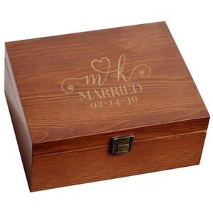 May include: A rectangular wooden box with a hinged lid and a metal clasp. The box is stained a warm brown color. The lid is engraved with the word "MARRIED", the date "02-14-30", and the initials "mk" with a heart symbol.