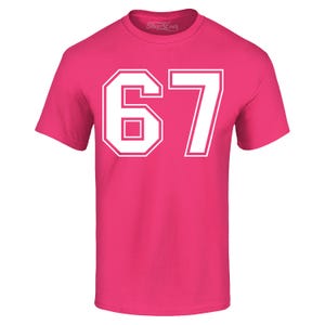 May include: A bright pink t-shirt with the number "67" printed in white block letters. The number is outlined in white. The shirt has short sleeves and a crew neck.