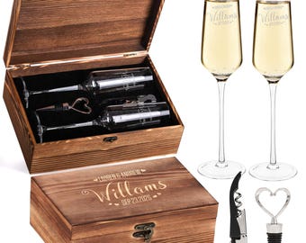 May include: A wooden gift box with a hinged lid, containing two champagne flutes, a bottle stopper, and two wine glasses. The box is engraved with a name and date. Two champagne flutes with the name "Williams" are filled with champagne. A corkscrew and a heart-shaped bottle stopper are also included.