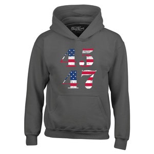 May include: A dark grey hooded sweatshirt with the numbers 45 and 47 printed on the front. The numbers are in a white font and are decorated with an American flag design.