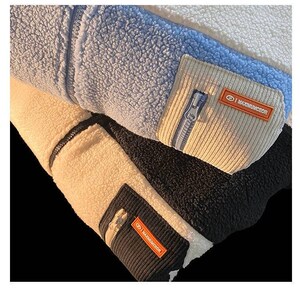 May include: Close-up of a cream, blue, and black fleece jacket with a zipper and a patch that says "MAXIMUMCUDOR".