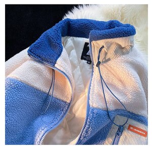 May include: A blue and white fleece jacket with a zipper closure and a corduroy collar. The jacket has a patch with the text "MAXIMUM DECOR" on the lower right side.