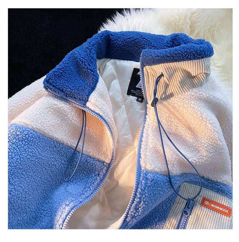 May include: A blue and white fleece jacket with a zipper closure and a corduroy collar. The jacket has a patch with the text "MAXIMUM DECOR" on the lower right side.