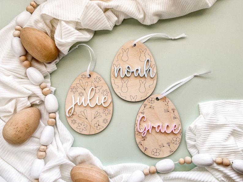 May include: Three wooden Easter egg ornaments with floral designs and names "Julie", "Noah", and "Grace" written in different colors.