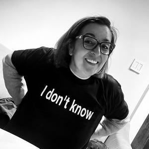 May include: A black short-sleeved t-shirt featuring the white text "I don't know" printed across the chest. The shirt has a crew neckline and is worn by an individual with dark hair and glasses, visible from the chest up in this black and white image.