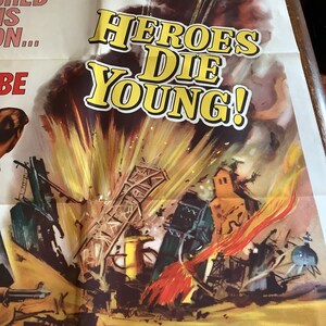 Op de afbeelding: Een vintage filmposter voor de film "Heroes Die Young". De poster toont een dramatische afbeelding van een grote explosie met een vurige rode en oranje rookpluim. De titel van de film is in grote gele letters op een witte achtergrond geschreven.