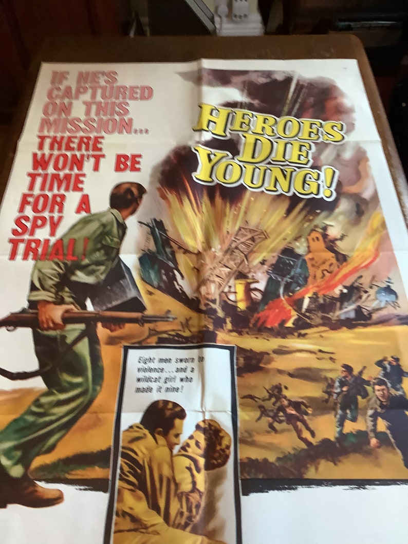 Op de afbeelding: Vintage filmposter voor de film "Heroes Die Young" met een dramatische sc&egrave;ne van een explosie met een soldaat die een geweer vasthoudt op de voorgrond. De tekst op de poster luidt: "Als hij tijdens deze missie wordt gevangen genomen... is er geen tijd voor een spionageproces!"