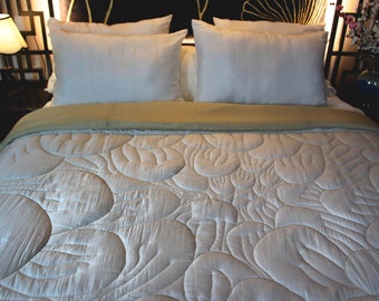May include: A white quilted duvet cover with a pattern of overlapping circles. The duvet cover is on a bed with two white pillows and a tan bedspread.