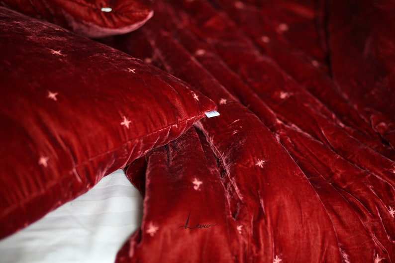 May include: Red velvet bedding with a subtle star pattern. The fabric is soft and luxurious, perfect for a cozy bedroom.