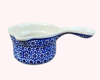 Puede incluir: Un servidor de salsa de cerámica blanca y azul con asa. El exterior presenta un patrón floral azul con detalles en blanco y naranja. El interior es blanco. Este plato para servir es ideal para salsas y salsas.