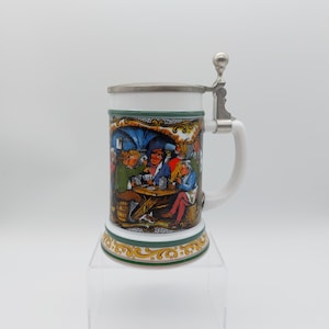 May include: White ceramic beer stein with a pewter lid and handle. The stein features a colorful illustration of people playing cards in a tavern.