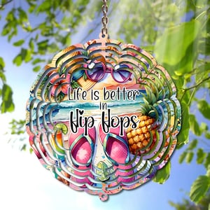 May include: A colorful, layered wind chime with a beach scene and the text "Life is better in flip flops". The wind chime features a pineapple, flip flops, sunglasses, and a beach umbrella.