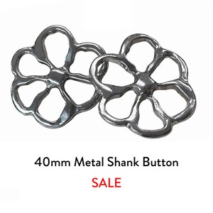 May include: Two silver metal shank buttons in a flower shape. Each button has six petals with open centres. The buttons are 40mm in diameter. The word "SALE" is printed in red below the buttons.