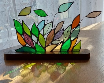 Panel de vitral con hojas sobre soporte de madera