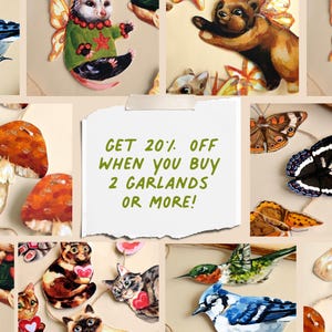 May include: A collection of decorative paper cutouts featuring illustrations of an opossum in a green sweater, a bear with wings, various butterflies, mushrooms, cats holding red hearts, a hummingbird, and a blue jay, with text reading GET 20% OFF WHEN YOU BUY 2 GARLANDS OR MORE!