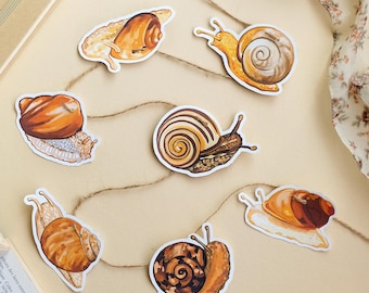 May include: A decorative garland featuring six distinct snail illustrations in various shades of brown, tan, and cream. Each snail cutout is attached to a thin, natural jute twine string, showcasing different shell patterns and body textures.