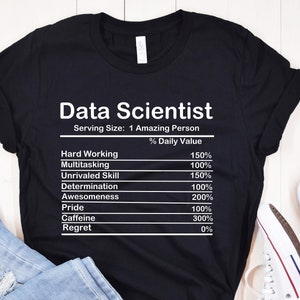 May include: Black t-shirt featuring the words "Data Scientist" and a nutrition facts label. The label lists qualities such as "Hard Working" and "Awesomeness" with percentage values. The shirt is displayed with jeans and a shoe.