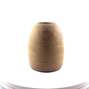 Può includere: Un vaso in ceramica marrone, strutturato, di forma ovale. Il vaso ha una base ampia che si restringe verso l'alto. La superficie ha un aspetto ruvido e macchiettato. Il vaso è alto circa 20 cm.