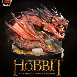 May include: A detailed statue of Smaug the dragon from The Hobbit: The Desolation of Smaug. The dragon is red and brown with sharp teeth and wings. The statue sits on a base of gold coins and stone blocks, with the movie title below.