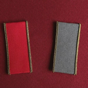 Könnte beinhalten: Zwei Stoffproben mit goldener Einfassung. Die Probe links ist rot und die Probe rechts ist grau.