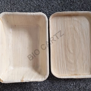 May include: Two rectangular, light brown, disposable plates made from palm leaves. The plates are made by Bio Cartz.