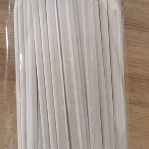 May include: A bundle of white paper straws wrapped in clear plastic. The straws are bundled together and ready to be used.