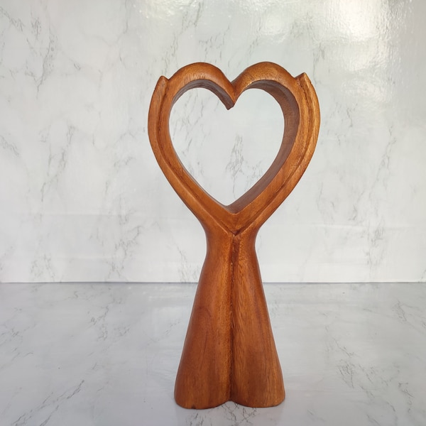 Statue of a hand holding a brown heart  Wooden statue of Hands Holding Heart. Symbol of Love two hands holding a heart. "Heart in Hands"