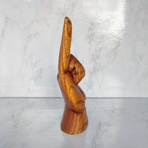 May include: A wooden hand sculpture with the index finger pointing up. The hand is carved from a light brown wood and has a natural finish.