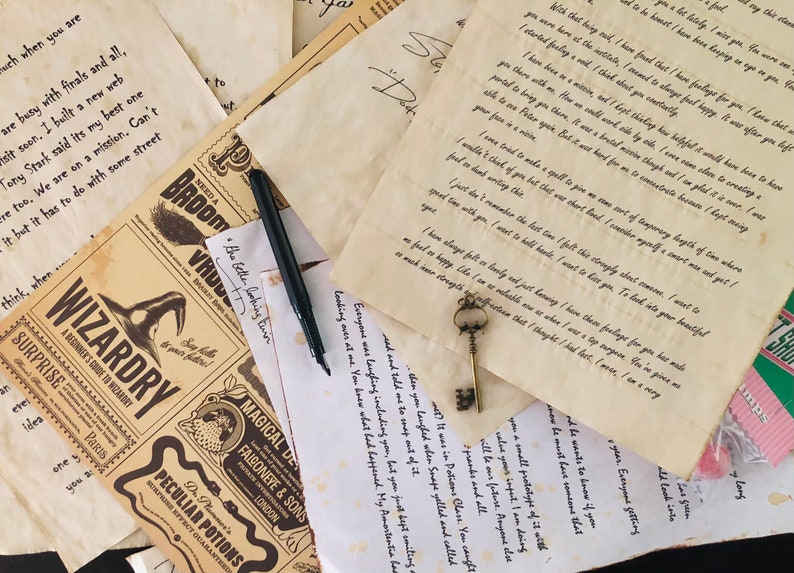 May include: A collection of aged, parchment-style papers featuring printed text and handwritten letters, a black fountain pen, and a small, ornate metal skeleton key. The papers include a Wizardry guide, potion labels, and personal correspondence.
