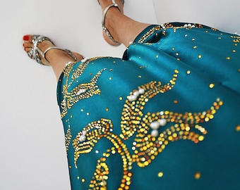 May include: A teal blue satin skirt with gold and white embellishments. The skirt has a beaded design with a floral pattern.