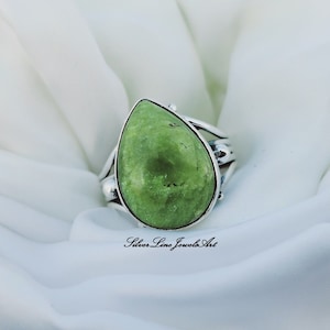 Peut inclure: Une bague en argent avec une pierre précieuse verte en forme de larme. La bague a une bande torsadée délicate.