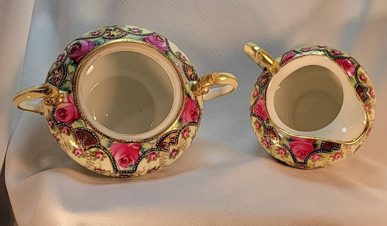 May include: A vintage porcelain sugar and creamer set with a floral design. The set features a gold trim and pink roses on a cream background.