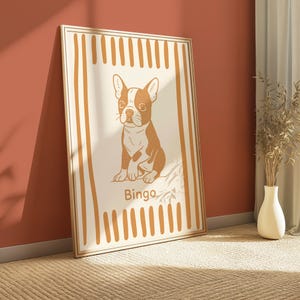 Puede incluir: Lámina enmarcada con ilustración de un perro Boston Terrier marrón y blanco sentado. El perro está sobre un fondo crema con rayas verticales marrones. La palabra "Bingo" está escrita en la parte inferior.