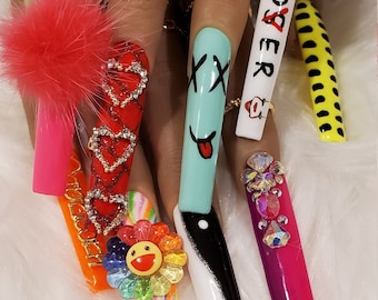 May include: Close-up of long, colorful, decorated fingernails. The nails are painted with various designs, including hearts, a smiley face, a yin-yang symbol, and the word "Loser".