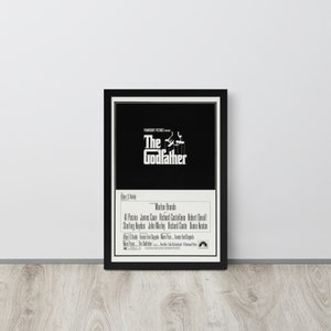 May include: A black and white movie poster for the film "The Godfather" featuring the title in bold white text and a silhouette of a man holding a puppet. The poster also includes the names of the actors, including Marlon Brando, Al Pacino, and James Caan.