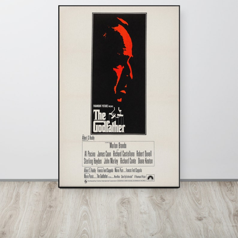 May include: A vintage movie poster for the film "The Godfather" featuring a red silhouette of Marlon Brando's face. The poster also includes the film's title, director, and cast.