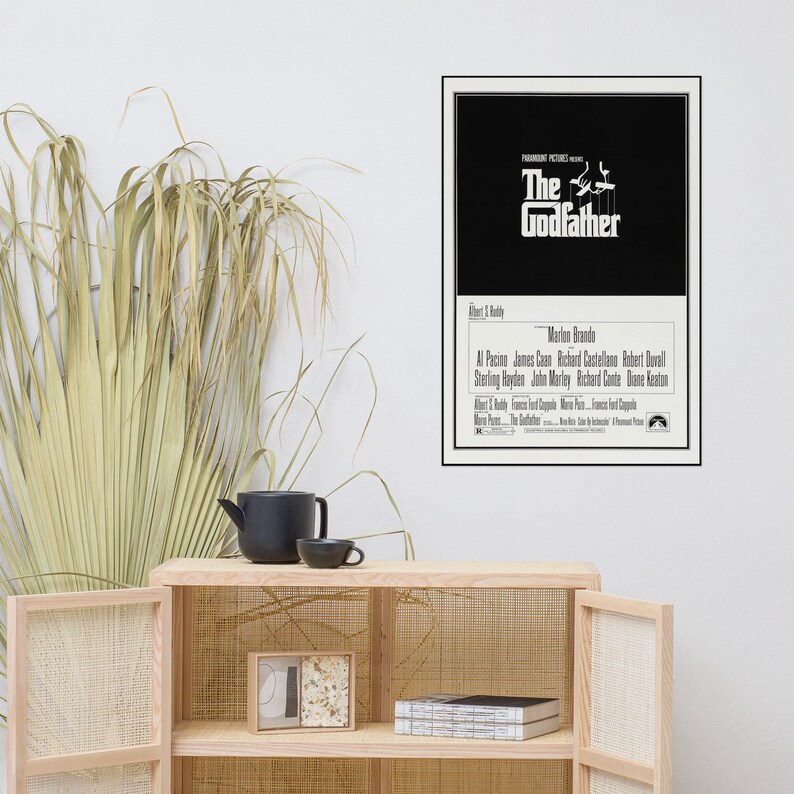 May include: A black and white movie poster for the film "The Godfather" featuring the title in a bold white font. The poster also includes the names of the actors, including Marlon Brando, Al Pacino, James Caan, and Robert Duvall.