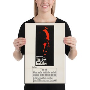 May include: A vintage movie poster for the film "The Godfather" featuring a red silhouette of Marlon Brando's character Don Vito Corleone. The poster includes the film's title, director, and cast.