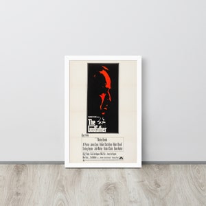 May include: A vintage movie poster for the film "The Godfather" featuring a red silhouette of Marlon Brando's face. The poster includes the film's title, director, and cast.