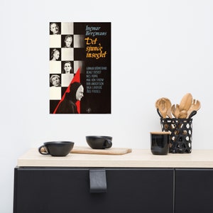 May include: A vintage movie poster for the film "The Seventh Seal" by Ingmar Bergman. The poster features a black and white checkered background with a red diagonal line. The title of the film is in white text with a black outline. The cast list is in white text on a black background. The poster is in a black frame.